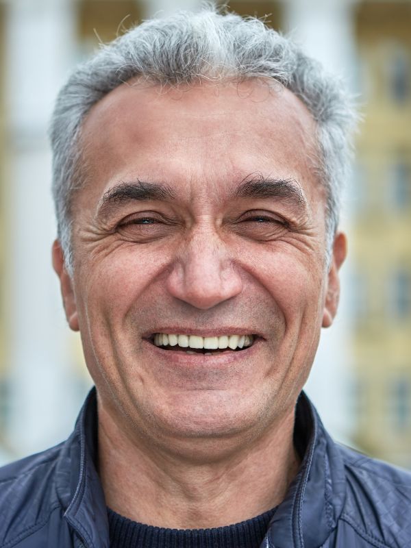 Older man smiling after dental implant treatment in Denver, Colorado