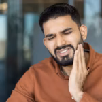 Man holding his jaw in pain and needing an emergency dentist in Denver