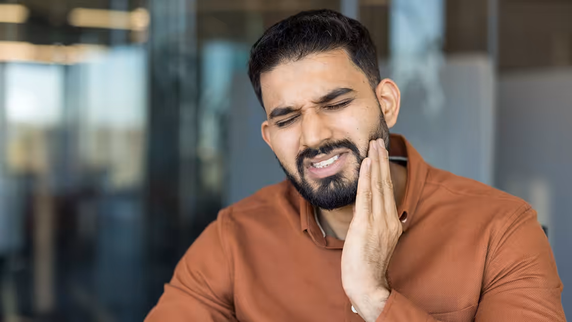 Man holding his jaw in pain and needing an emergency dentist in Denver