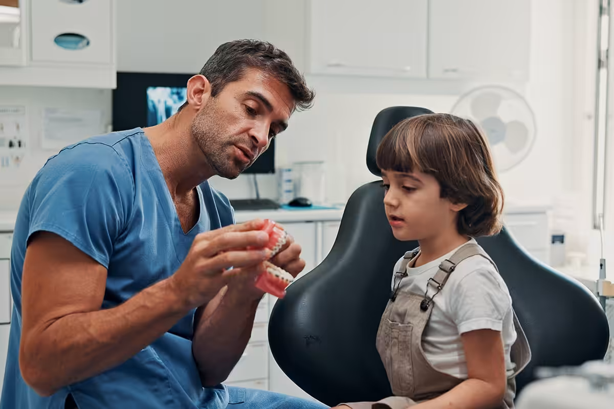 Denver dentist showing a young patient a model of teeth during a routine dental exam